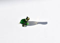 May include: A small green glass turtle figurine with black eyes. The turtle is sitting on a white surface and casting a shadow.