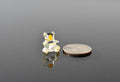 May include: A small, clear glass bear figurine with black eyes and a yellow nose. The figurine is sitting on a reflective surface and is next to a silver US quarter.