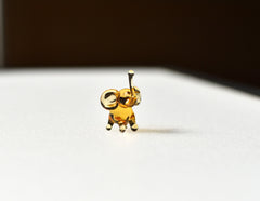 May include: A small, gold-colored glass elephant figurine with a raised trunk. The elephant is standing on a white surface.