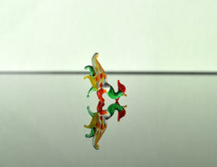 May include: A small glass figurine of a rooster with green, yellow, orange, and red colors. The rooster is standing on a reflective surface.