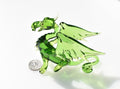 May include: A green glass dragon figurine with wings outstretched. The dragon has a long tail curled underneath its body. The dragon is about the size of a quarter.