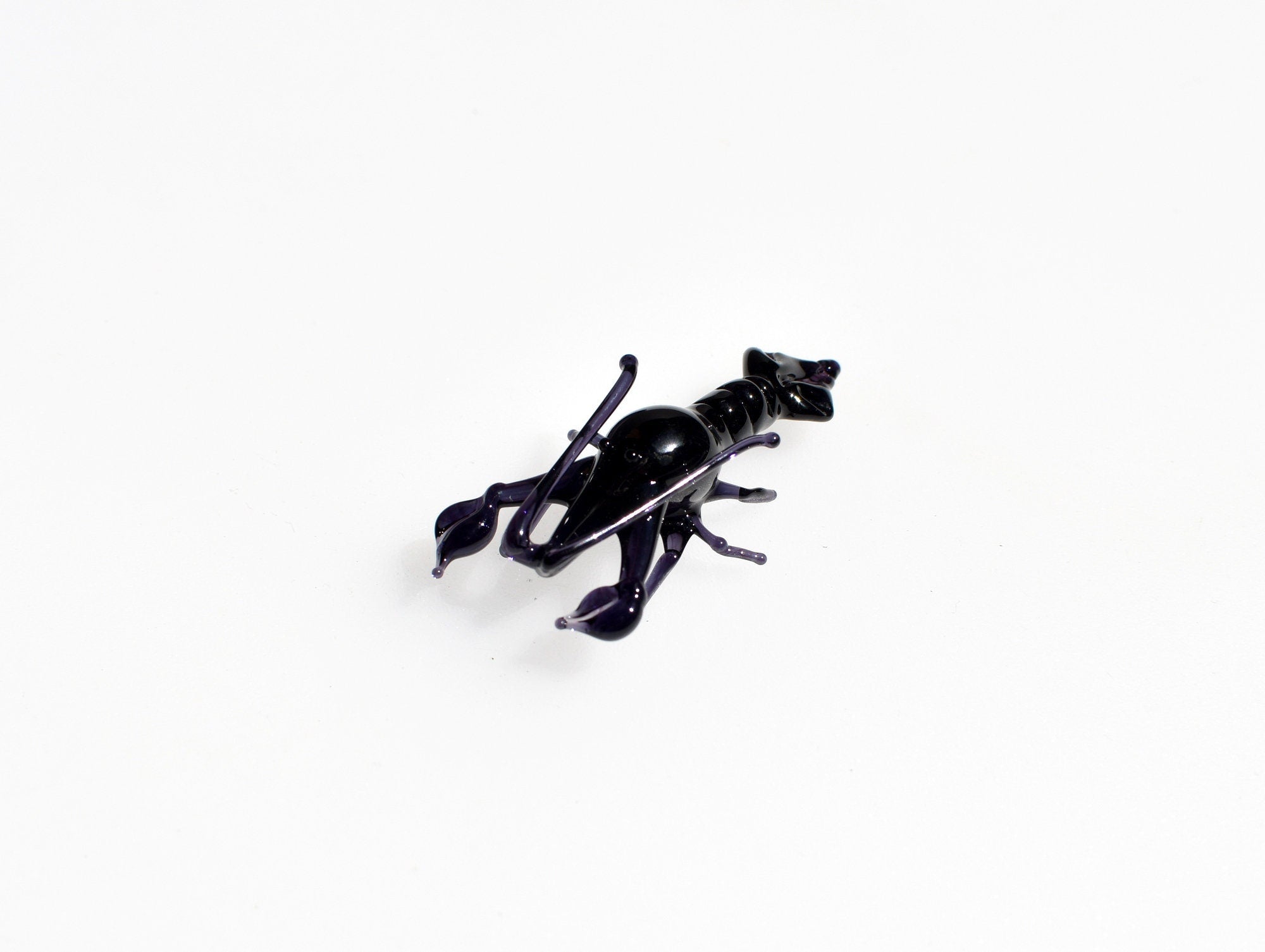 May include: A black glass lobster figurine with a purple hue.