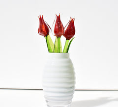 May include: Three red glass tulips in a white, ribbed vase.