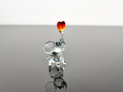 May include: A glass elephant figurine with a red and orange heart on its trunk.